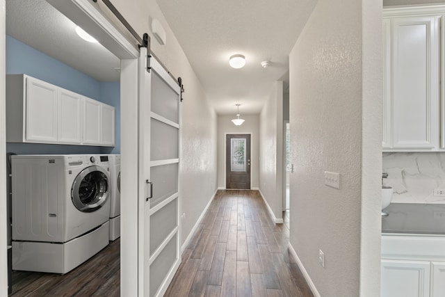 laundry room featuring cabinets, separate washer and dryer, a textured ceiling, dark hardwood / wood-style flooring, and a barn door