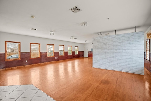 unfurnished room featuring light hardwood / wood-style flooring and brick wall