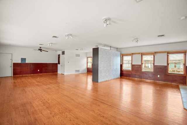 empty room featuring a wealth of natural light, ceiling fan, and light hardwood / wood-style floors