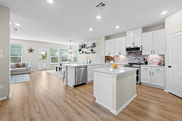 kitchen featuring hanging light fixtures, a center island, white cabinets, and stainless steel appliances