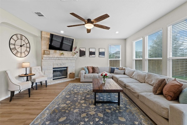 living room with hardwood / wood-style floors, ceiling fan, and a fireplace