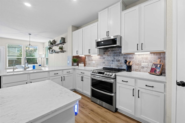 kitchen featuring white cabinetry, an inviting chandelier, light hardwood / wood-style floors, decorative light fixtures, and appliances with stainless steel finishes