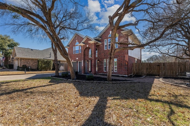 traditional home featuring a front yard, brick siding, and fence