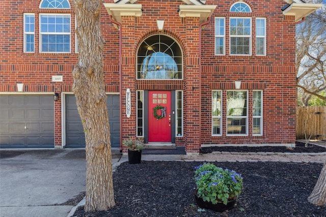 doorway to property with driveway, an attached garage, and brick siding