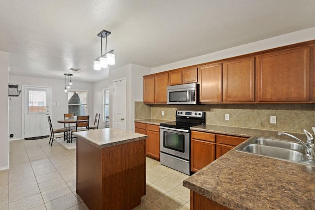 kitchen with sink, a center island, pendant lighting, decorative backsplash, and appliances with stainless steel finishes