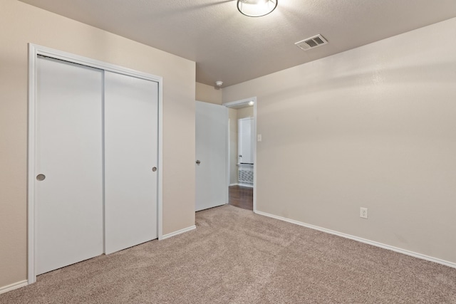 unfurnished bedroom with light carpet, a textured ceiling, and a closet