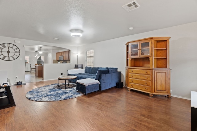 living room with a textured ceiling and dark hardwood / wood-style floors