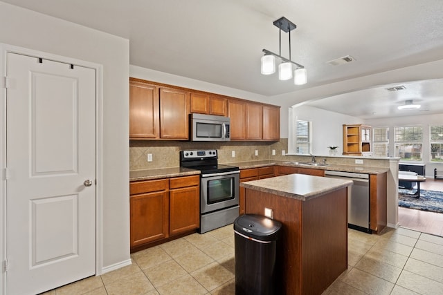 kitchen with decorative backsplash, stainless steel appliances, sink, a center island, and hanging light fixtures