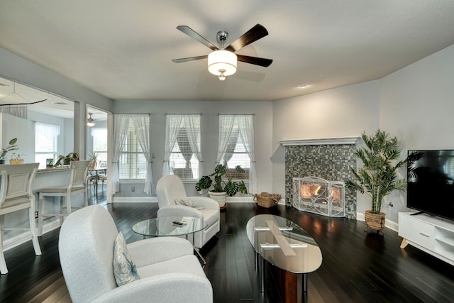 living room with ceiling fan, dark wood-type flooring, a wealth of natural light, and a tiled fireplace