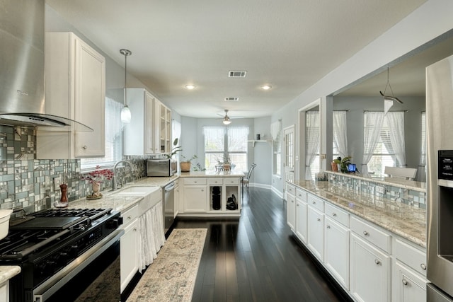 kitchen with white cabinets, stainless steel appliances, light stone countertops, and wall chimney range hood