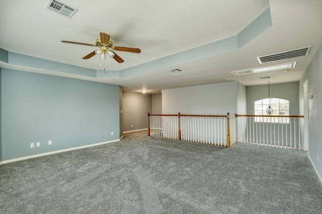 carpeted empty room featuring a raised ceiling and ceiling fan