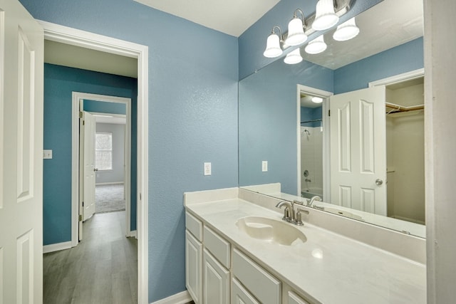 bathroom with hardwood / wood-style flooring, vanity,  shower combination, and a chandelier