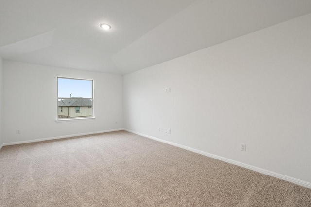 carpeted empty room with lofted ceiling