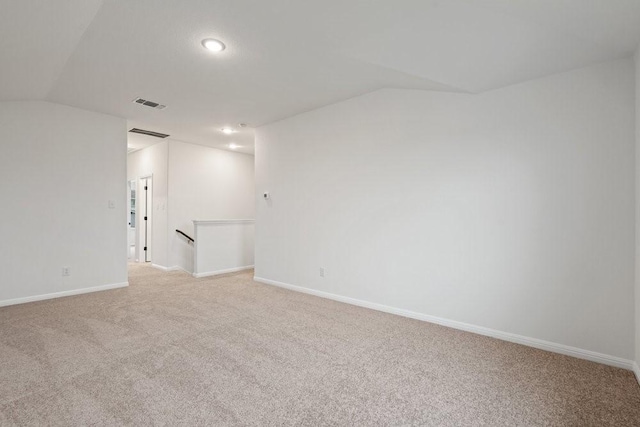 carpeted spare room with vaulted ceiling