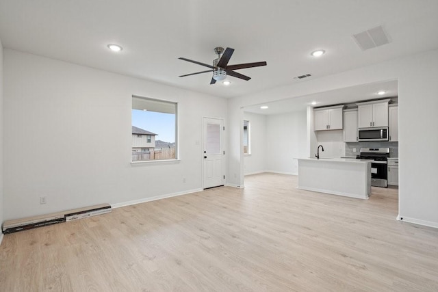 unfurnished living room with light hardwood / wood-style flooring, ceiling fan, and sink