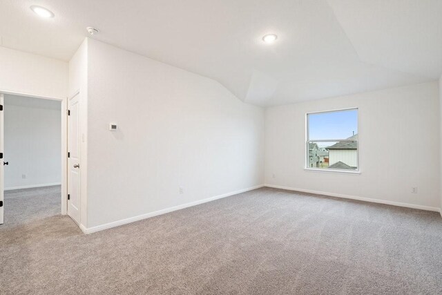 spare room featuring light carpet and vaulted ceiling