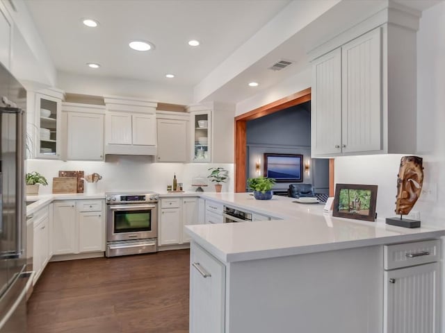 kitchen with kitchen peninsula, dark hardwood / wood-style flooring, white cabinets, and stainless steel range with electric cooktop