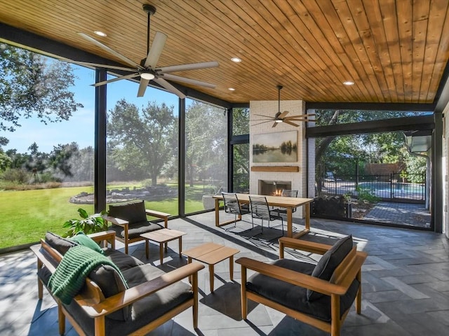 sunroom / solarium with a tile fireplace, lofted ceiling, a wealth of natural light, and wooden ceiling