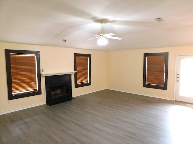 unfurnished living room with ceiling fan, dark hardwood / wood-style flooring, and a tile fireplace