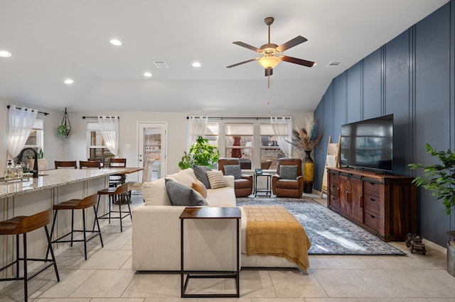 living room featuring ceiling fan, sink, light tile patterned floors, and lofted ceiling