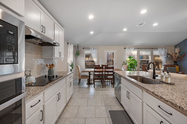 kitchen featuring dishwasher, black electric stovetop, sink, vaulted ceiling, and white cabinetry