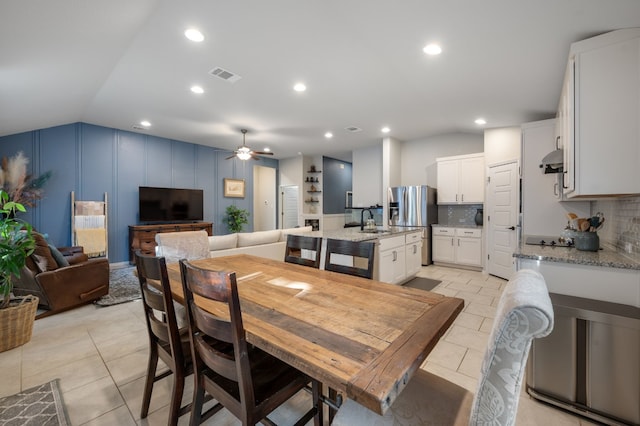 tiled dining room with ceiling fan, sink, and lofted ceiling