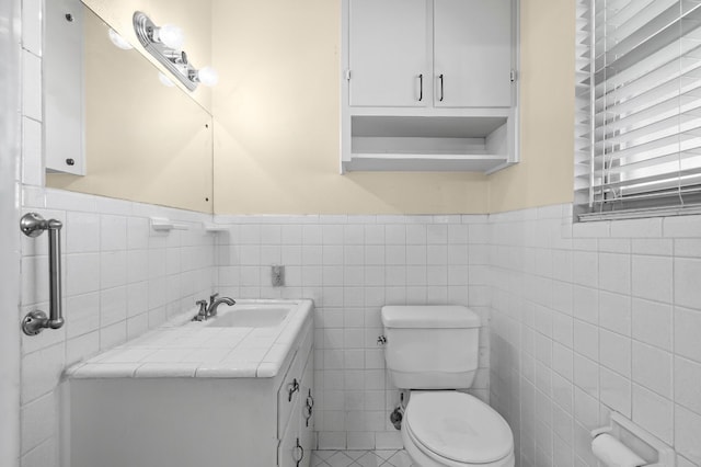 bathroom with vanity, toilet, and tile walls