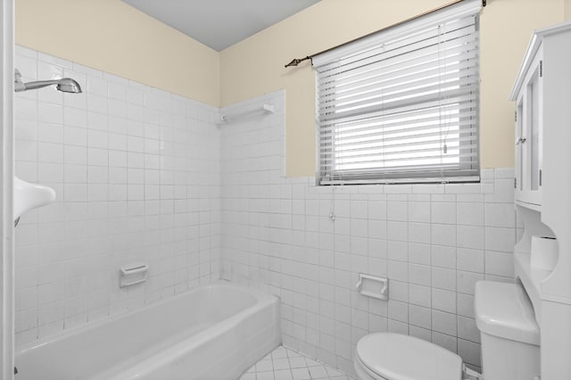 bathroom with tile patterned floors, tiled shower / bath combo, toilet, and tile walls