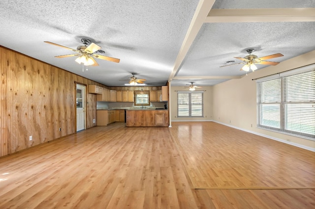 901 Berrywood Dr, Austin, TX 78753 - unfurnished living room with a textured ceiling, ceiling fan, wood walls, light wood-style flooring, and baseboards