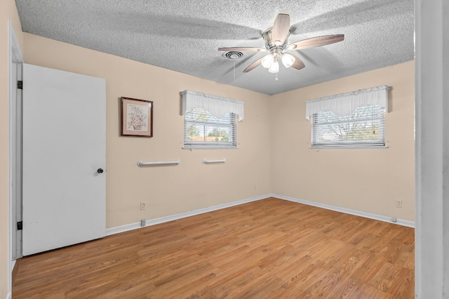 empty room featuring a textured ceiling, light hardwood / wood-style flooring, and ceiling fan