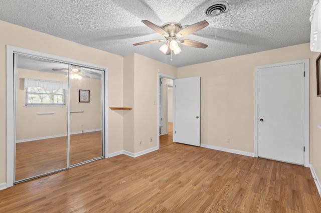 unfurnished bedroom with a textured ceiling, a closet, light hardwood / wood-style floors, and ceiling fan