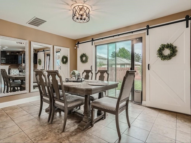 dining area featuring a chandelier, a barn door, and light tile patterned flooring