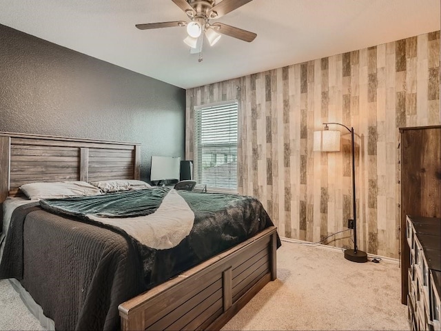 bedroom with ceiling fan, wood walls, and light carpet