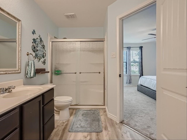 bathroom featuring toilet, a shower with shower door, vanity, ceiling fan, and hardwood / wood-style floors