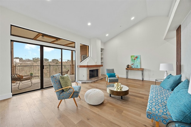 living room featuring vaulted ceiling, light wood-type flooring, and built in shelves