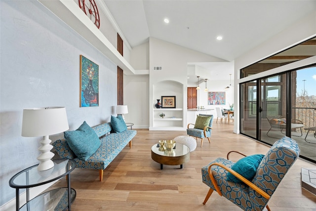 living room featuring high vaulted ceiling, built in shelves, and light hardwood / wood-style flooring