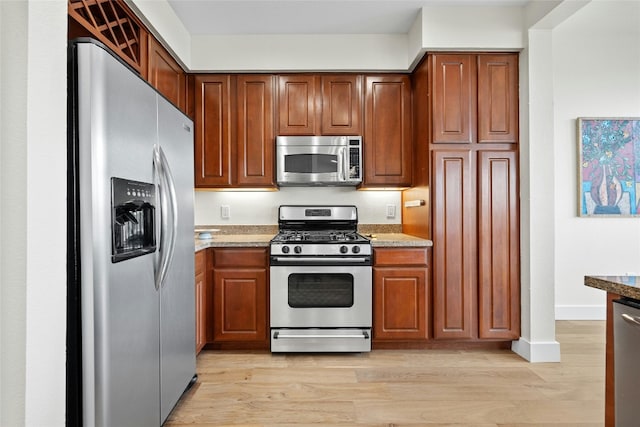 kitchen with light stone counters, stainless steel appliances, and light hardwood / wood-style flooring