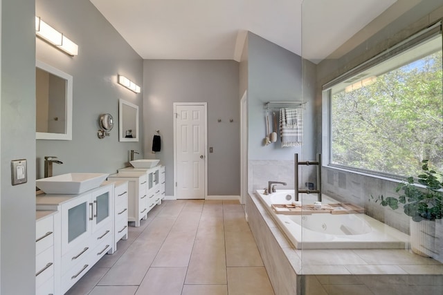 bathroom with tile patterned flooring, vanity, and tiled bath