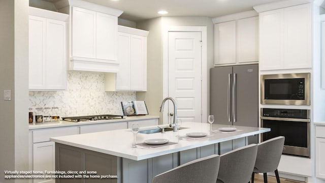 5612 Kyle Joseph Dr, Georgetown, TX 78628 - kitchen featuring stainless steel appliances, decorative backsplash, a breakfast bar area, light countertops, and white cabinetry