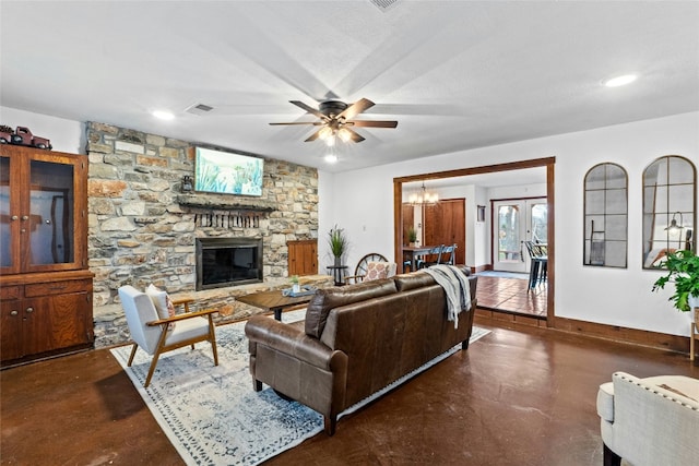 living room with ceiling fan with notable chandelier and a fireplace