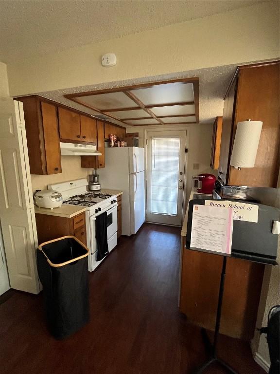 kitchen featuring a textured ceiling, white appliances, and dark wood-type flooring