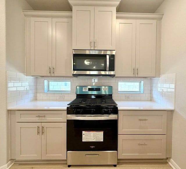 kitchen with stainless steel appliances, white cabinetry, and tasteful backsplash