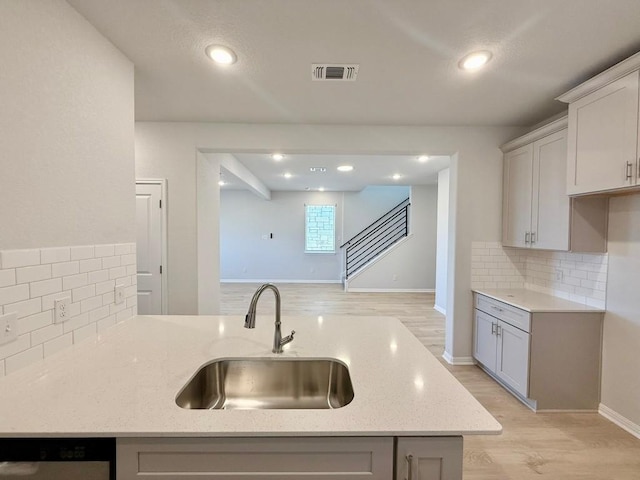 kitchen featuring light stone countertops, kitchen peninsula, backsplash, sink, and dishwasher