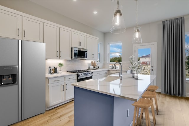 832 Venus Cir, Round Rock, TX 78664 - kitchen with appliances with stainless steel finishes, tasteful backsplash, an island with sink, light wood finished floors, and recessed lighting