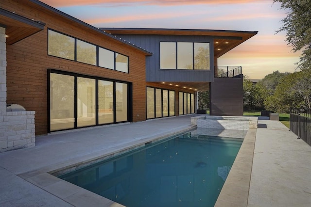 back house at dusk with a patio and a fenced in pool