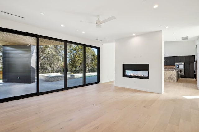 unfurnished living room featuring ceiling fan and light hardwood / wood-style flooring