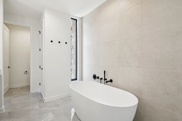 bathroom with a tub and tile walls