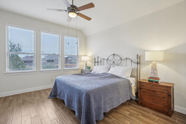 bedroom featuring ceiling fan, vaulted ceiling, and multiple windows