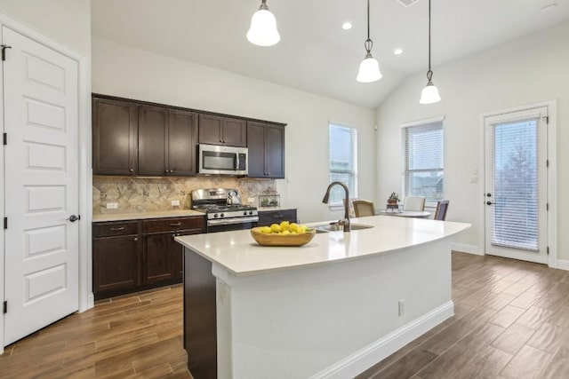 kitchen featuring a kitchen island with sink, sink, hanging light fixtures, and appliances with stainless steel finishes