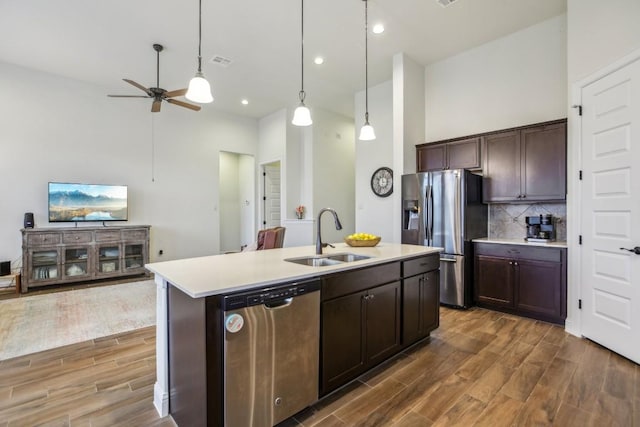 kitchen featuring appliances with stainless steel finishes, dark brown cabinets, ceiling fan, sink, and a center island with sink